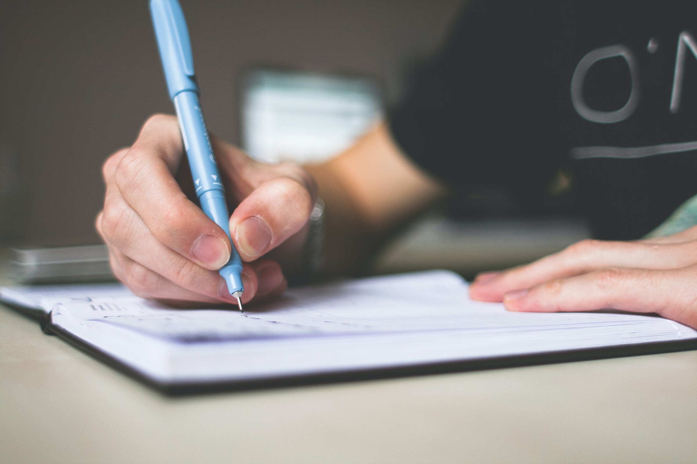 Une main écrivant sur une liste - Photo par picjumbo.com sur Pexels