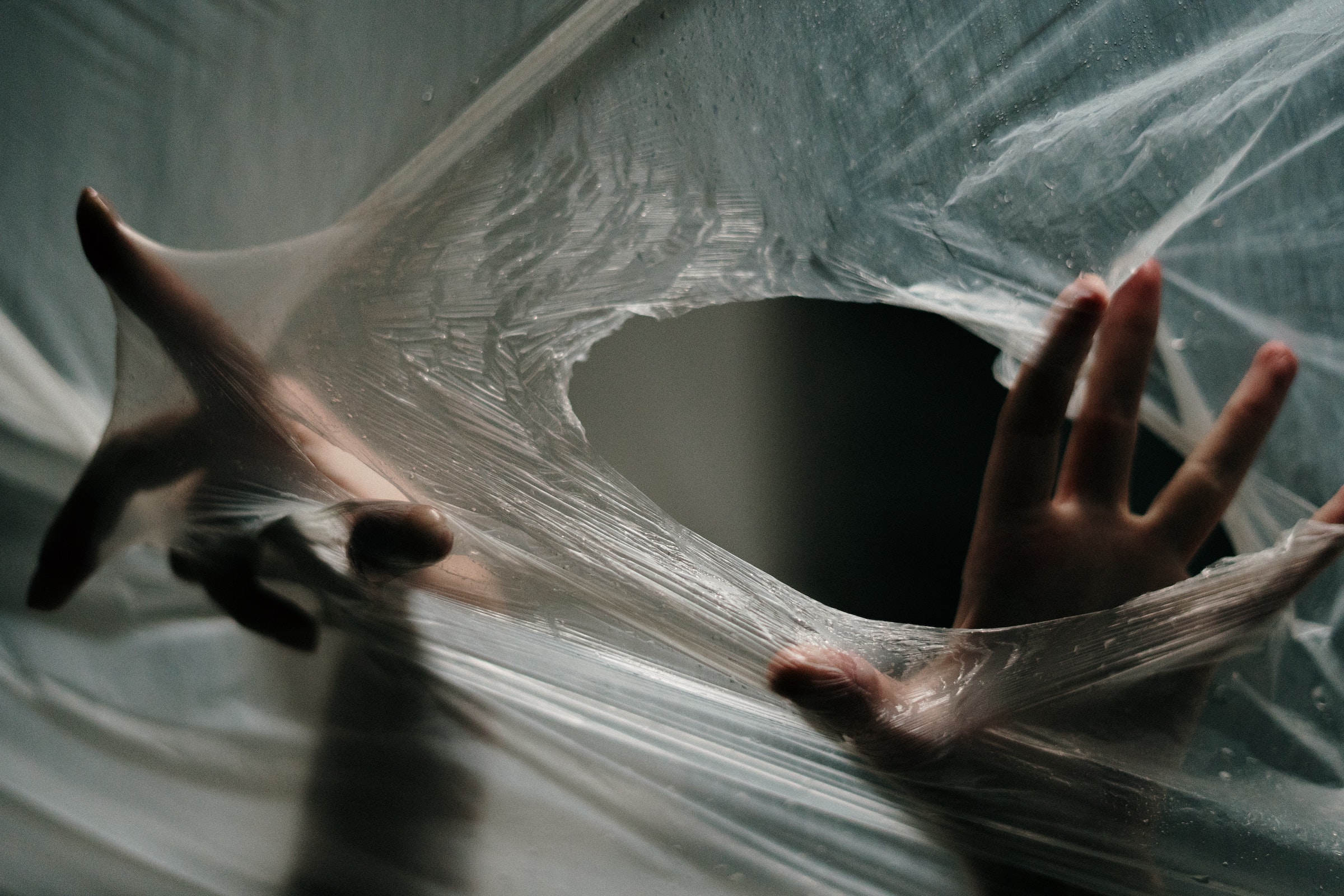 Pièges à pourriel - photo de mains passant à travers un trou dans une feuille de plastique transparent