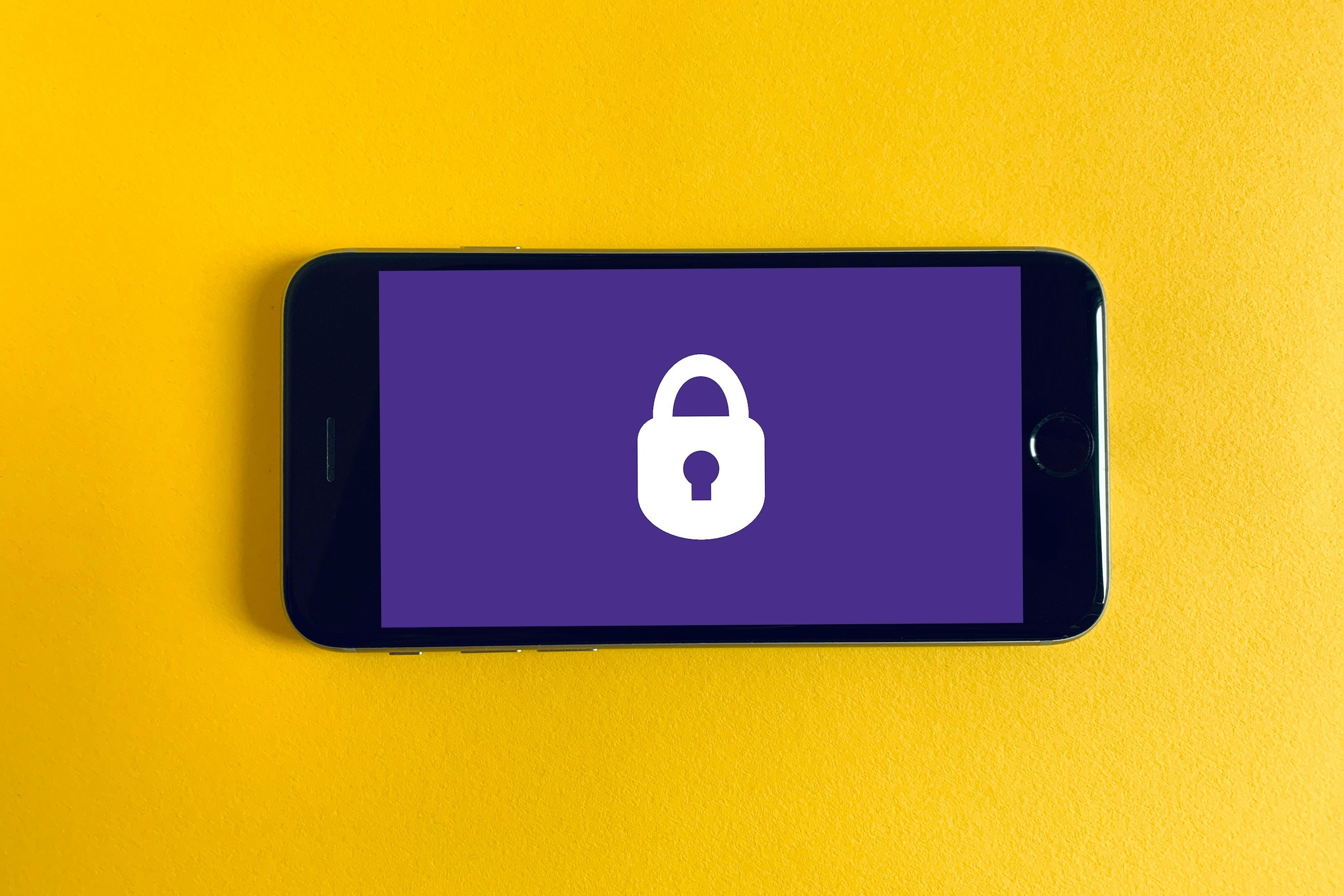 Iphone noir sur fond jaune avec un cadenas. Photo de Franck sur Unsplash
